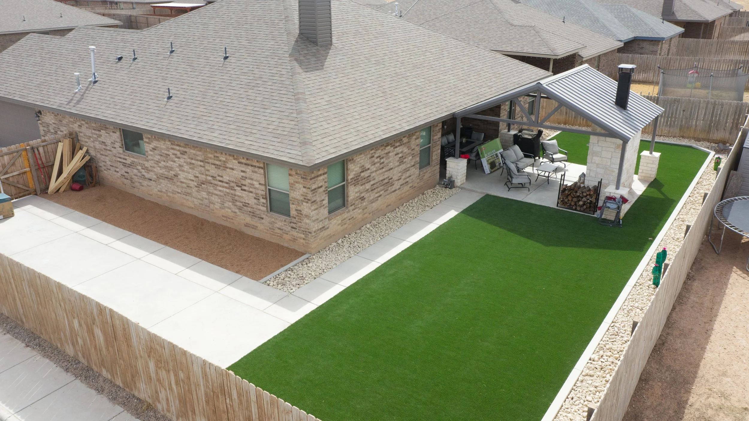 Completed outdoor living space with artificial turf and custom patio in Odessa, TX
